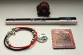 A composition of a Chinese red tortoise figurine, a black and white pen, a bracelet with a yin yang symbol and a metal magnet.