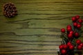 Composition of Christmas pinecone, branches of Hollies on green wooden background.