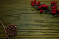 Composition of Christmas pinecone, branches of Hollies on green wooden background.