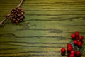 Composition of Christmas pinecone, branches of Hollies on green wooden background.