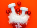 Composition with Christmas stocking, white dumbbells on red background.