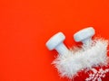 Composition with Christmas stocking, white dumbbells on red background.