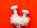 Composition with Christmas stocking, white dumbbells on red background.