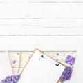 Composition with clipboard, diary, lilac flowers, gift and accessories on wooden background. Flat lay, top view Royalty Free Stock Photo