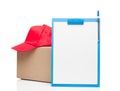 Composition with clipboard red cap and cardboard box Royalty Free Stock Photo