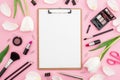 Composition with clipboard, tulips, cosmetics and accessory on pink background. Top view. Flat lay. Home feminine desk.