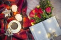 Composition: a cup of coffee tea, red roses with boxwood, a book, candles, a garlands