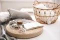 Composition with cup of drink, cotton and book on wicker pouf