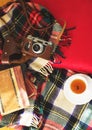 Composition with cup of tea, vintage camera, old books on sofa with plaid. Top view.