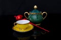 Composition of cup and teapot and a symbolic object of christmas on a black background