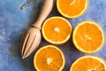 Composition from cut in half ripe juicy colorful oranges with wood reamer on blue concrete background