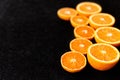 A composition of cut in halves oranges and tangerines on a black background