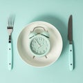 Composition with cutlery, plate and alarm clock on color background. Diet concept