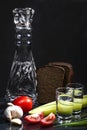 Composition with a decanter of vodka, two glasses with a reflection of sliced cucumber, garlic, tomatoes and black bread. Black Royalty Free Stock Photo