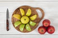 Composition of different color apples on wooden cutting board and knife next to it in top view Royalty Free Stock Photo