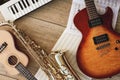 Composition of different musical instruments: synthesizer, electronic guitar, saxophone and ukulele lying, sheets with
