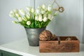 Composition of dried artichoke flowers in wooden box and a bouquet of white tulips in a vase as home decoration. Modern style flow Royalty Free Stock Photo