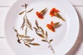 A composition of dried marigold flowers and leaves on white plate. Royalty Free Stock Photo