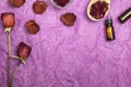Composition of dried red roses, rose petals and dark bottle on a purple paper background. Dry red flowers and petals in a wooden Royalty Free Stock Photo