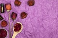 Composition of dried red roses, rose petals and dark bottle on a purple paper background. Dry red flowers and petals in a wooden Royalty Free Stock Photo