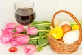 Composition for Easter. Wicker basket with eggs, a bouquet of pink tulips, a glass of dry wine.