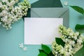 Composition with empty green envelope and beautiful spring lilac flowers on mint background. Mockup card invitation Royalty Free Stock Photo