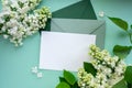 Composition with empty green envelope and beautiful spring lilac flowers on mint background. Mockup card invitation Royalty Free Stock Photo