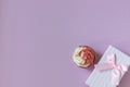 Composition with festive cupcake with pink cream and gift box on pink background. Natural light.