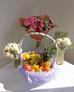 Composition of a festive white table with bouquets of flowers and a basket of fruits. Royalty Free Stock Photo