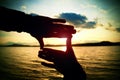 Composition finger frame- man's hands capture sunset at sea. Multicolored horizontal outdoors image.