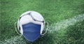 Composition of football with face mask on grass with copy space