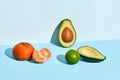 Composition of fresh fruits, mandarin lime and two halfs of cutted avocado on two-colored background Royalty Free Stock Photo