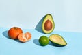 Composition of fresh fruits, mandarin lime and two halfs of cutted avocado on two-colored background Royalty Free Stock Photo