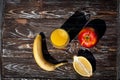 Composition of fresh fruits and orange juice in a glass. A banana, an apple and half a lemon.