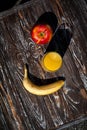 Composition of fresh fruits and orange juice in a glass. A banana and apple lie on a textured wooden table Royalty Free Stock Photo