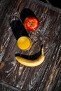 Composition of fresh fruits and orange juice in a glass. A banana and red apple lie on a table