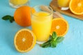 Composition with fresh orange juice in glass, mint, wooden juicer and oranges on color background, closeup Royalty Free Stock Photo