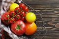 Composition of fresh ripe tomatoes of different varieties, spices, basil, rosemary, thyme, hot pepper in a basket on a wooden boar Royalty Free Stock Photo