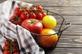 Composition of fresh ripe tomatoes of different varieties, spices, basil, rosemary, thyme, hot pepper in a basket on a wooden boar Royalty Free Stock Photo