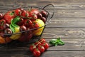 Composition of fresh ripe tomatoes of different varieties, spices, basil, rosemary, thyme, hot pepper in a basket on a wooden boar Royalty Free Stock Photo