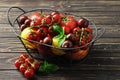 Composition of fresh ripe tomatoes of different varieties, spices, basil, rosemary, thyme, hot pepper in a basket on a wooden Royalty Free Stock Photo