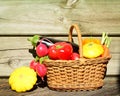 Composition with fresh vegetables arranged in a wicker basket on a wooden table