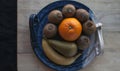 Composition of fruits on a decorative blue platter on a wooden board with a black cloth in the background Royalty Free Stock Photo