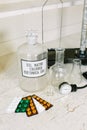 Glass bottle with latin label of isotonic solution, blister packs of different tablets, scales, glass flask and