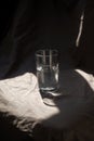 Composition glass cup half filled with water on a cloth background. Hard light. Trend color