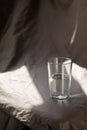 Composition glass cup half filled with water on a cloth background. Hard light. Trend color