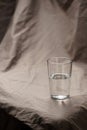 Composition glass cup half filled with water on a cloth background. Soft light