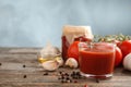 Composition with glass of tasty tomato sauce on wooden table against color background Royalty Free Stock Photo