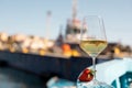 Composition of glass with white wine and strawberry putting on board of blue wooden boat on sunny day. Soft focus. Royalty Free Stock Photo