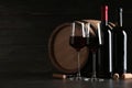 Composition with glasses and bottles of red wine on table against dark background Royalty Free Stock Photo